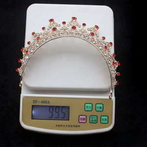 Detailed view of luxury gold bridal crown with red crystals on electronic scale weighing 99.5g
