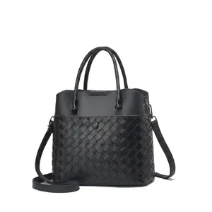 Detail of black leather handbag featuring classic woven texture and cylindrical top handles
