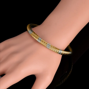 Two-tone twisted cable cuff bracelet in gold and silver finish worn on wrist