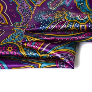 Detailed macro of purple paisley silk scarf fabric showing elegant satin gloss and texture