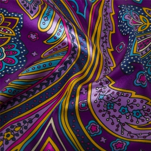 Close-up of bohemian silk-like scarf with detailed purple paisley and floral patterns