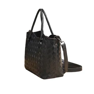 Dettaglio ravvicinato di una borsa in pelle intrecciata nera con doppi manici e metallo