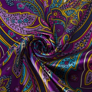 Close-up of bohemian silk scarf with purple paisley floral pattern and satin texture