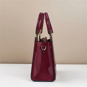 Detail of the deep red patent leather finish and golden hardware on the handbag