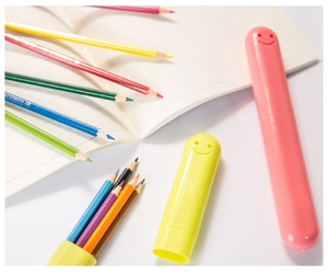 Pink and yellow cylindrical cases with 3D smiley face detail for toothbrushes or pens