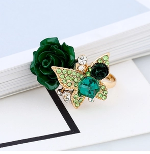 Macro shot of gold butterfly and rose ring with green crystal on book pages