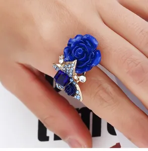 Macro shot of blue rose ring with butterfly design and square zircon on a golden band