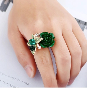 Close-up of vintage emerald rose ring with green enamel flower and crystals on gold band
