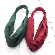 Flat lay of vintage style velvet cross-twist headbands in dark green and burgundy colors