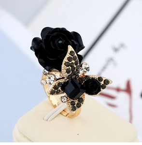 Macro view of vintage gold ring with a black rose, butterfly, and square gemstone