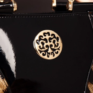 Macro shot of black patent leather handbag featuring a gold hollow circular metal logo