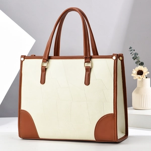 Close-up of beige patchwork tote bag showing brown leather corners and gold metal rings