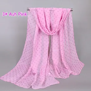 Detail of grey polka dots on light pink chiffon scarf hanging on a metal rack