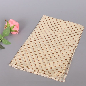 Detail of soft cream chiffon scarf with brown polka dots and lightweight texture