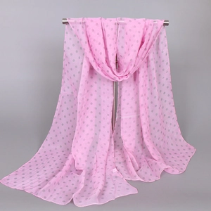 Pink chiffon scarf with grey polka dots hanging on a metal rack showing drape texture