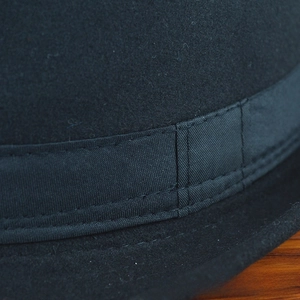 Détail de la couture sur un chapeau fedora en feutre noir avec un ruban en gros-grain