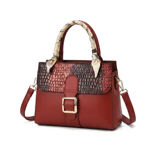 Détail de la texture crocodile noire et cuir rouge du sac à main avec boucle dorée chic