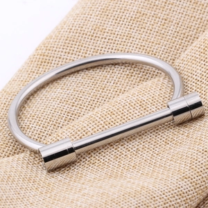 Polished silver stainless steel horseshoe D-shape bangle on textured linen background