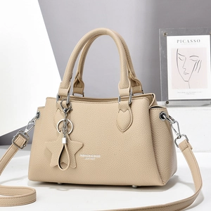 Gros plan détaillé du sac à main en cuir beige avec garnitures argentées et pompon étoile