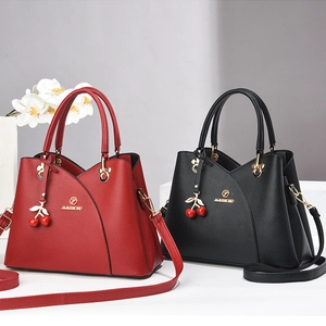Détail de sacs bandoulière rouge et noir avec pendentif cerise et accents dorés chic