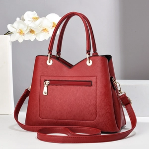 Détail d'un sac à main rouge en cuir grainé avec finitions dorées brillantes
