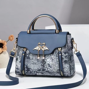 Détail de la broderie et du fermoir cygne en métal avec perles sur le sac bleu marine