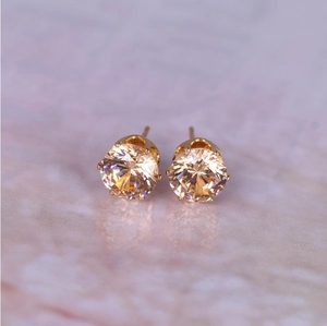 Close-up of 8mm round champagne zircon stud earrings with gold six-prong setting detail