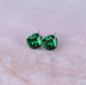 Macro view of forest green zircon stud earrings with classic silver-tone claw setting