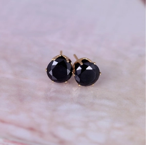 Macro detail of 8mm round black zircon earrings with gold-plated four-prong setting