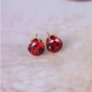 Close-up of red zircon stud earrings with classic gold-plated six-claw setting