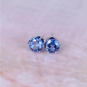 Macro shot of silver prong setting with 8mm round brilliant cut deep blue zircon earrings