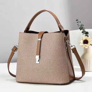 Detail der Vintage-Eimertasche aus braunem Leder mit gewebtem Stoffmuster und Riemen