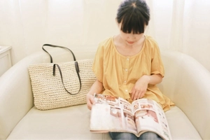 Close-up of a large straw woven tote bag with slim black handles for summer travel