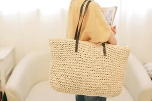 Minimalist straw woven tote bag for beach vacations with dark brown shoulder straps
