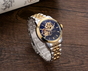 Detail of BYINO skeleton watch dial with gold accents on a dark wood background