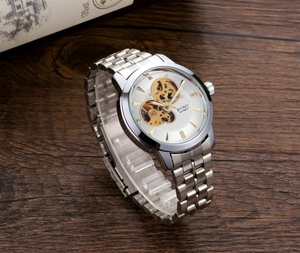 Detail of silver skeleton automatic mechanical watch on a stand with visible gold movement