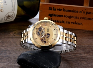 Close-up of a two-tone automatic skeleton watch with golden accents on a dark stone base