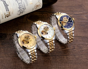 Three men's automatic watches with skeleton dials and gold-silver bands on wood