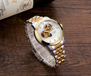 Close-up of skeleton automatic watch with gold movement and two-tone stainless strap