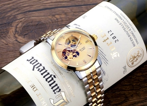 Detail of automatic mechanical watch with gold skeleton dial resting on a wine bottle