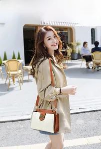 Detail of high-end bucket bag showing woven texture, tan leather trim, and golden metal buckle
