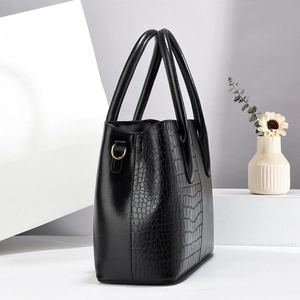 Detail of black faux crocodile skin texture and gold metal ring on a large tote bag