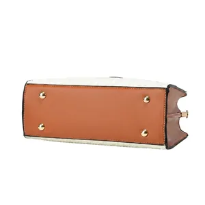 Detail view of the handbag bottom showing protective gold rivets and orange leather texture