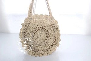 Detailed view of beige circular woven shoulder bag with intricate hollow crochet pattern