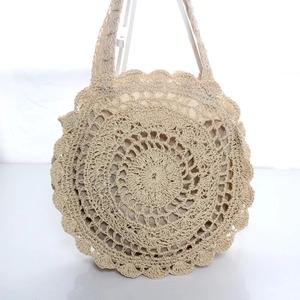 Handcrafted round straw woven beach bag with hollow crochet pattern and stylish wave edges