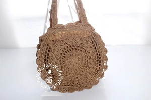 Detail of hand-crocheted paper rope beach bag with floral hollow patterns and wavy edges