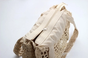Detail shot of the secure zipper closure and fabric lining on the woven straw tote bag