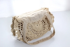 Detail of hand-woven straw beach bag featuring crochet floral pattern and zipper closure