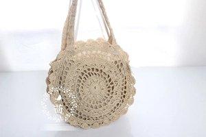 Detail showing beige crochet mandala flower pattern on a round woven straw beach tote bag