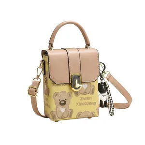 Detail of a mini yellow crossbody bag with brown bear print and cute bear keychain